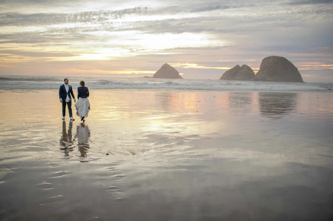 Photographer for wedding near me a bride and groom stand on wet sand that looks like a rough mirror reflecting the couple, the sky and the sunset