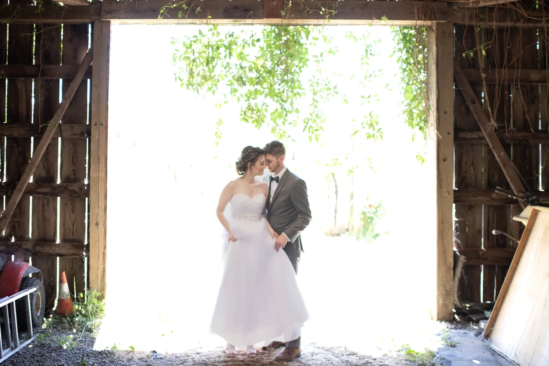 Vineyard Wedding Oregon with the bride and groom standing at the entrance of a barn in glowing white light