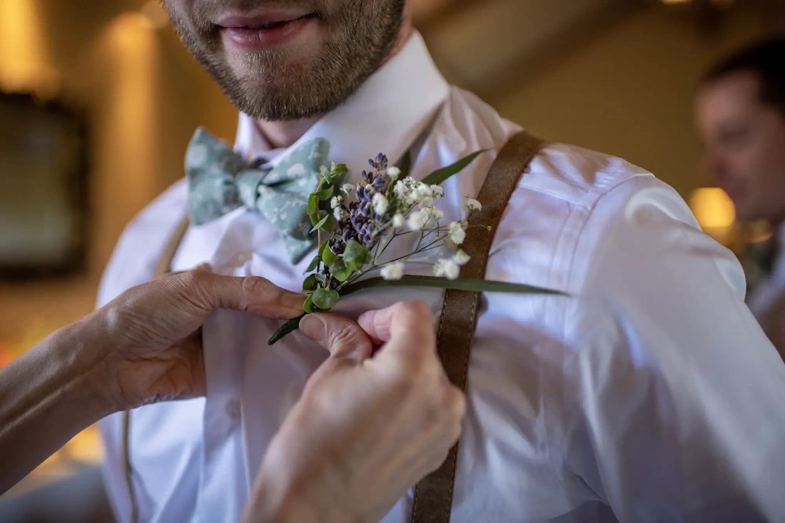 ​Vineyard Wedding Oregon were a close up photo of a groomsman having a boutonniere pinned on his shirt. 