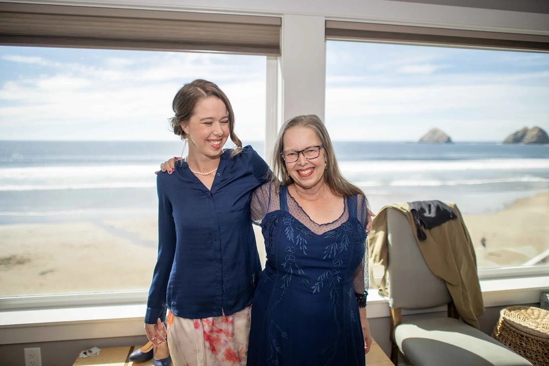 Wedding Photographers Near Me | Modern Art Photograph Wedding Photography from Oceanside, Oregon mother of the bride poses with the bride. The ocean is exposed perfectly outside in the sun.