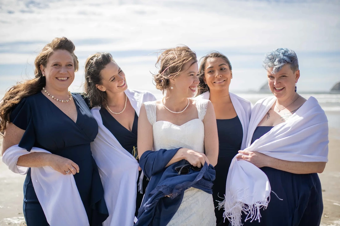 Wedding Photographers Near Me | Modern Art Photograph Wedding Photography from Oceanside, Oregonbride stands with her bridesmaids on the beach in the strong wind Wedding Photography from Oceanside, Oregon Wedding Photographers Near Me | Modern Art Photograph