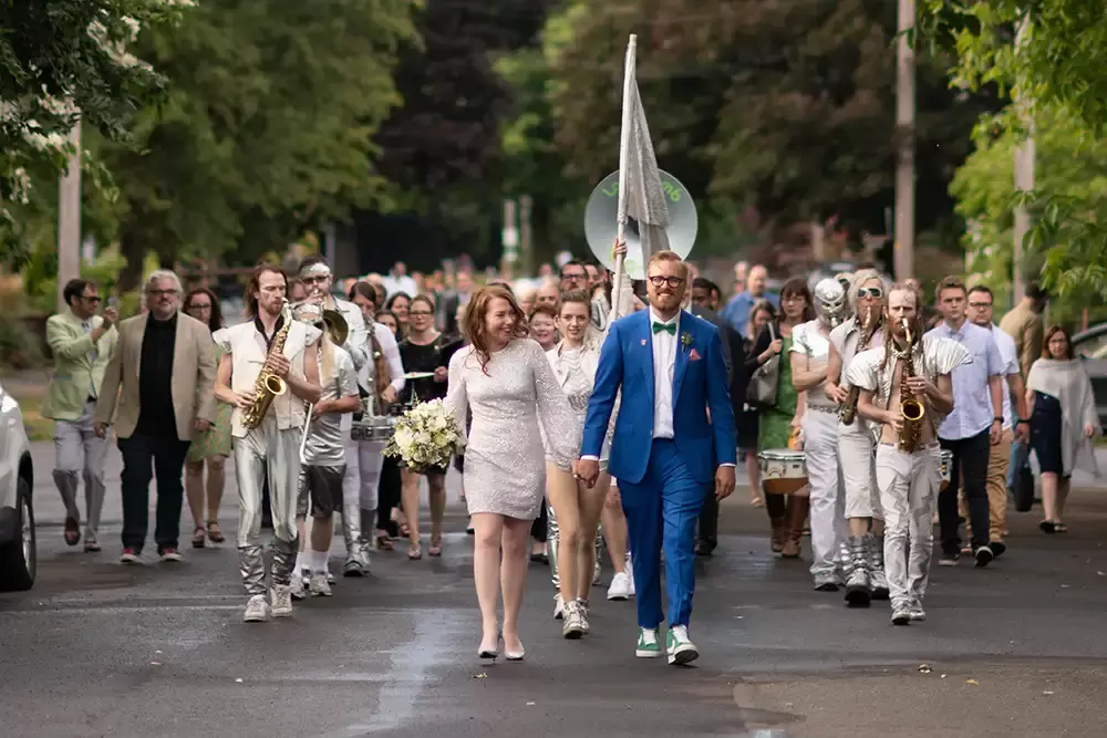 Portland Wedding Photographer Robert Knapp captures a couple just married leading a marching band from the park where they were married to the reception hall. 