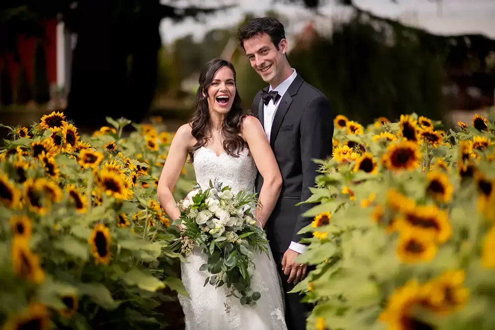 standing in between two rows of sunflowers a bride and groom stand at A ​Sauvie Island Wedding from Photographer ​Robert Knapp 