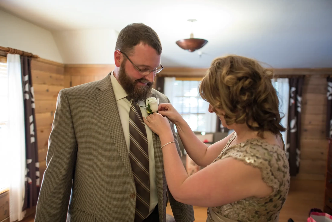 Wedding at Timberline Lodge, the bride pins a rose on the lapel of the groom