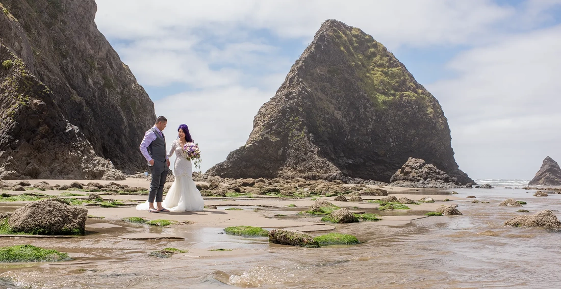 Bridal Photos at Cannon Beach by Photographer Robert Knapp a couple stands in the tide pools of cannon beach