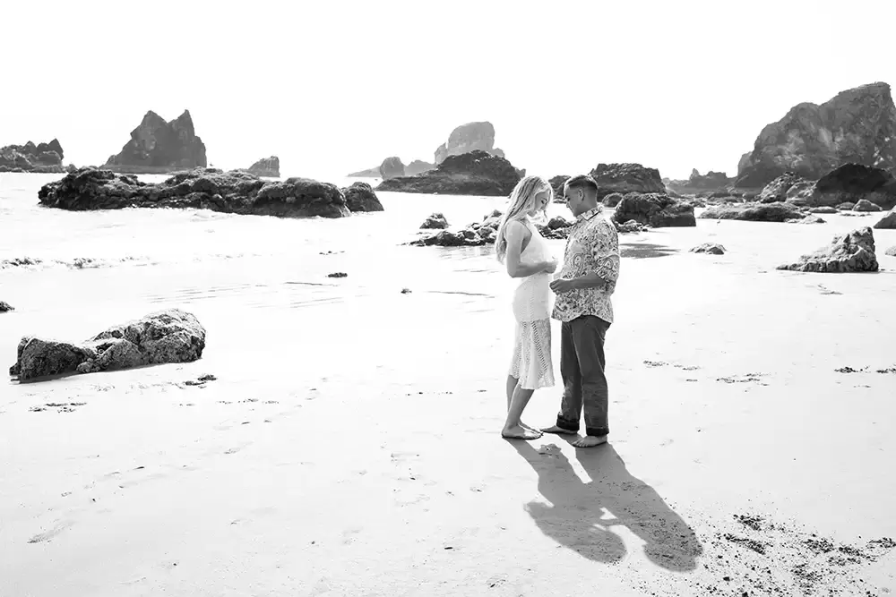 a man and woman stand on the beach together dCannon Beach Engagement Photos With Photographer Robert Knapp