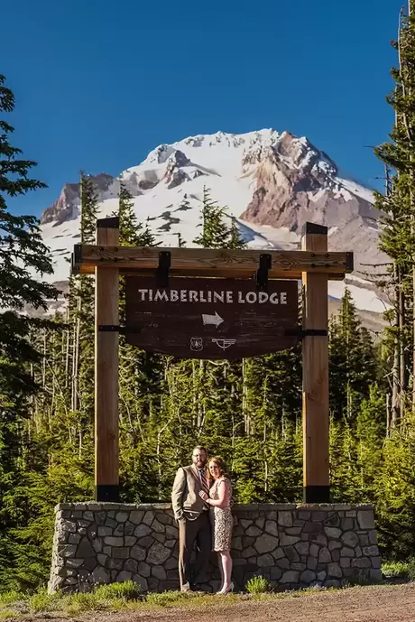 Wedding at Timberline Lodge a bride and groom stand in front of Mount Hood with the Timberline lodge sign