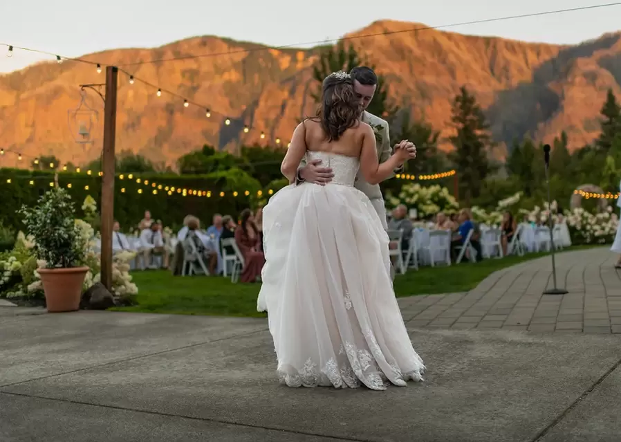 First Dance of married couple at Cape Horn Estate outdoor wedding. Sunset on the mountains in the background guests seated in the reception b