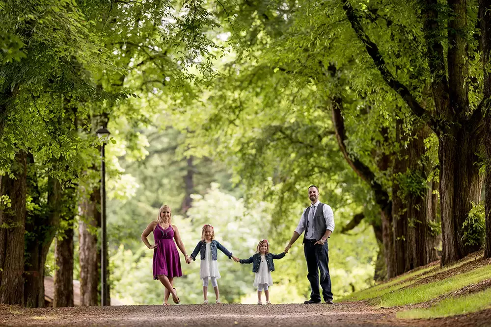 a family of four stands across a road holding hands Garden Photoshoot with Robert Knapp one of the highly sought after Family Photographers Portland has to offer