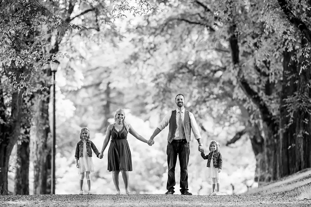 a family hold hands on a dirt road smiling toward the camera Garden Photoshoot with Robert Knapp one of the highly sought after Family Photographers Portland has to offer