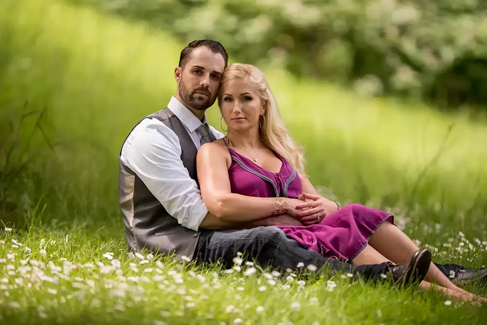 husband and wife sit in the park together among the wild flowers Garden Photoshoot with Robert Knapp one of the highly sought after Family Photographers Portland has to offer