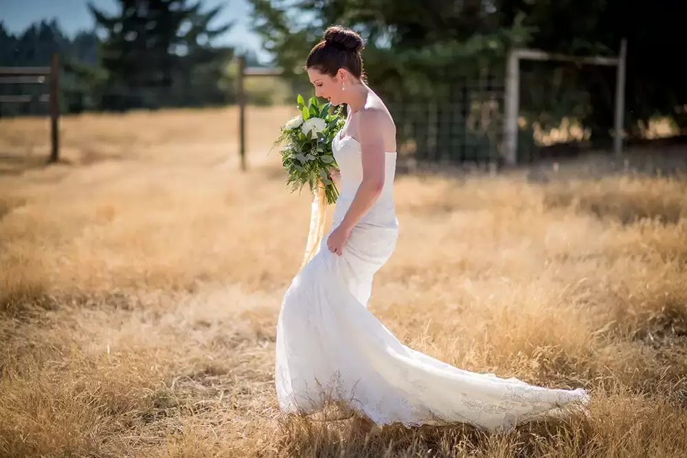 Farm Wedding Oregon
Rustic ​Chic Style with Robert Knapp Photographer bride makes her way through a rough field of brown grass. The full train of the wedding dress is dragging behind her in the brush. 