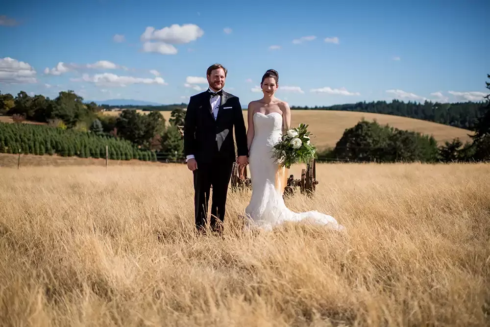 Farm Wedding Oregon
Rustic ​Chic Style with Robert Knapp Photographer bride and groom stand in a great amber field with rolling hills, blue sky and puffy white clouds in the distance. the white dress and black tux a great contrast to the natural setting. 