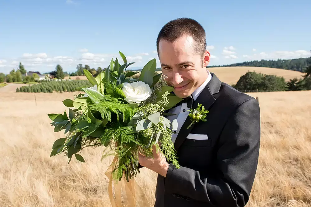 The best man holds the brides bouquet near his face and makes a curious sneaky smile. Keeping a light hearted sense of humor about the day makes things so much fun. 