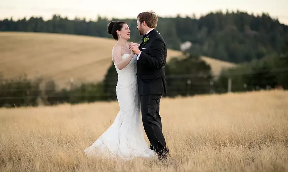 the couple dances in the middle of a field at sunset. 
