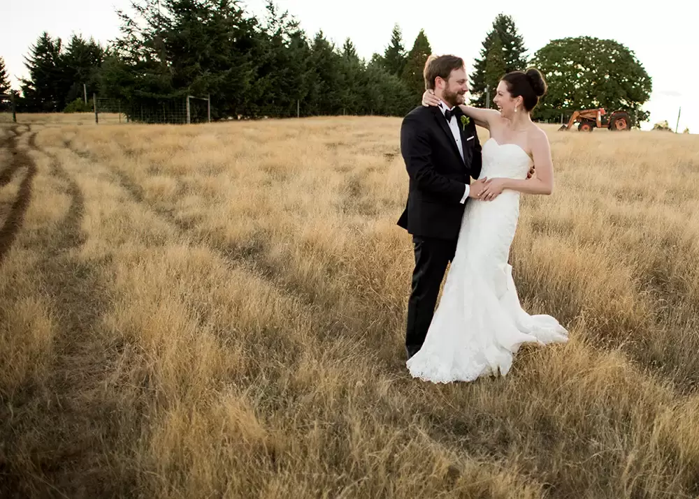 the bride and groom stand in the field. the grass have a sharp contrast. 
