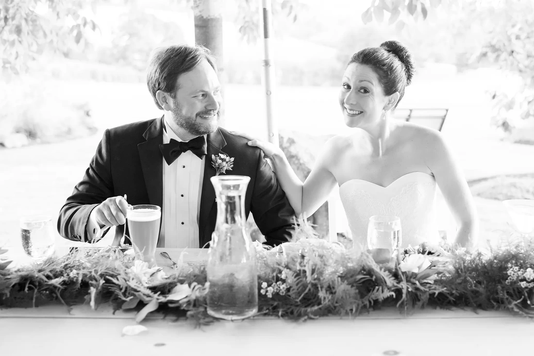 Farm Wedding Oregon Rustic ​Chic Style with Robert Knapp Photographer bride and groom sit to dinner. They smile at the camera.