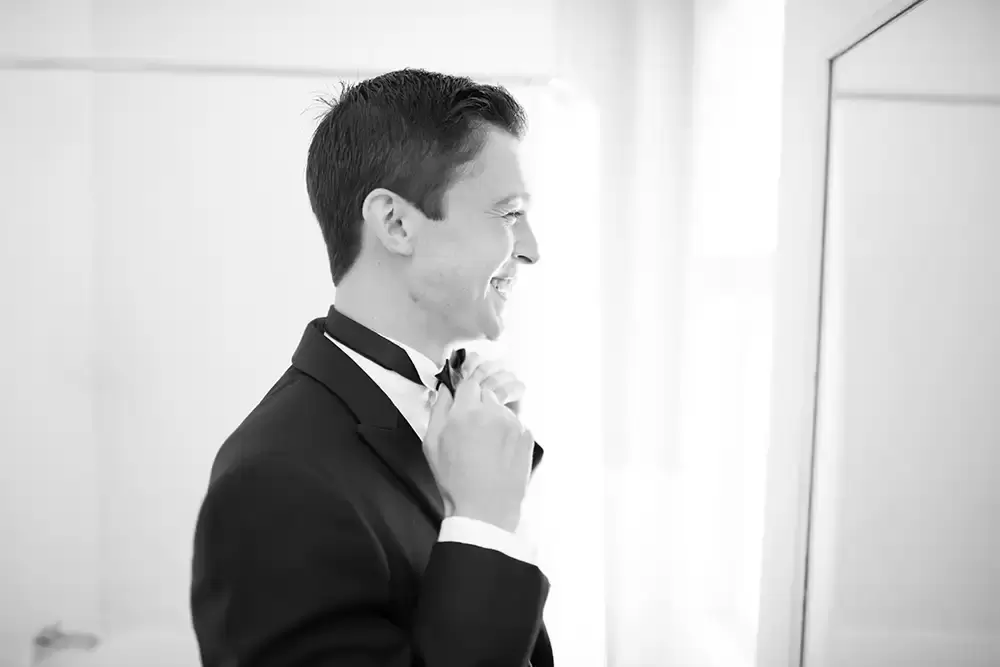 Hotel Deluxe Wedding in Portland Oregon
by Photographer Robert Knapp the groom is tying his bowtie with a very big smile