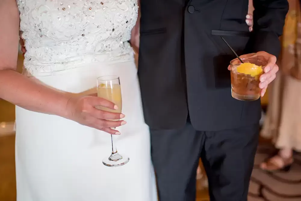 Hotel Deluxe Wedding in Portland Oregon
by Photographer Robert Knapp the bride and groom hold a drink in front of the the suit and dress