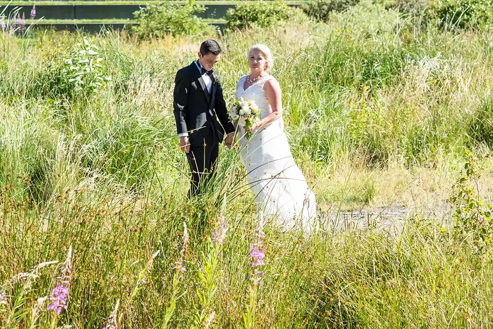 Hotel Deluxe Wedding in Portland Oregon
by Photographer Robert Knapp bride and groom dressed well stand in tall unkept grasses