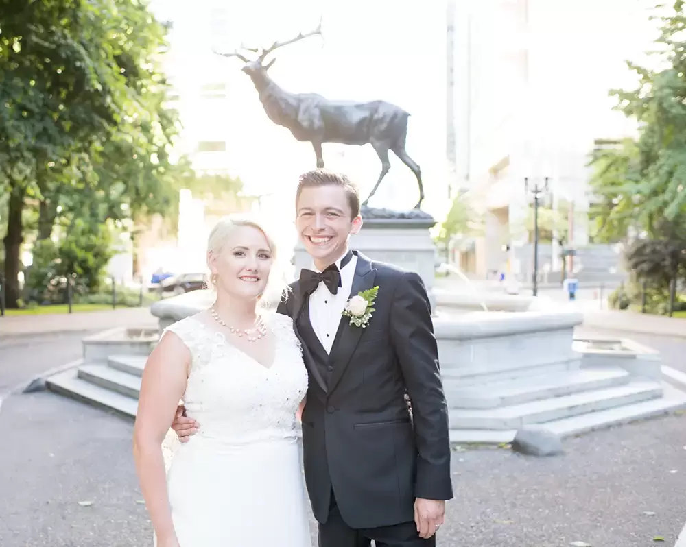 Hotel Deluxe Wedding in Portland Oregon
by Photographer Robert Knapp bride and groom pose with a smile in front of the bronze stag