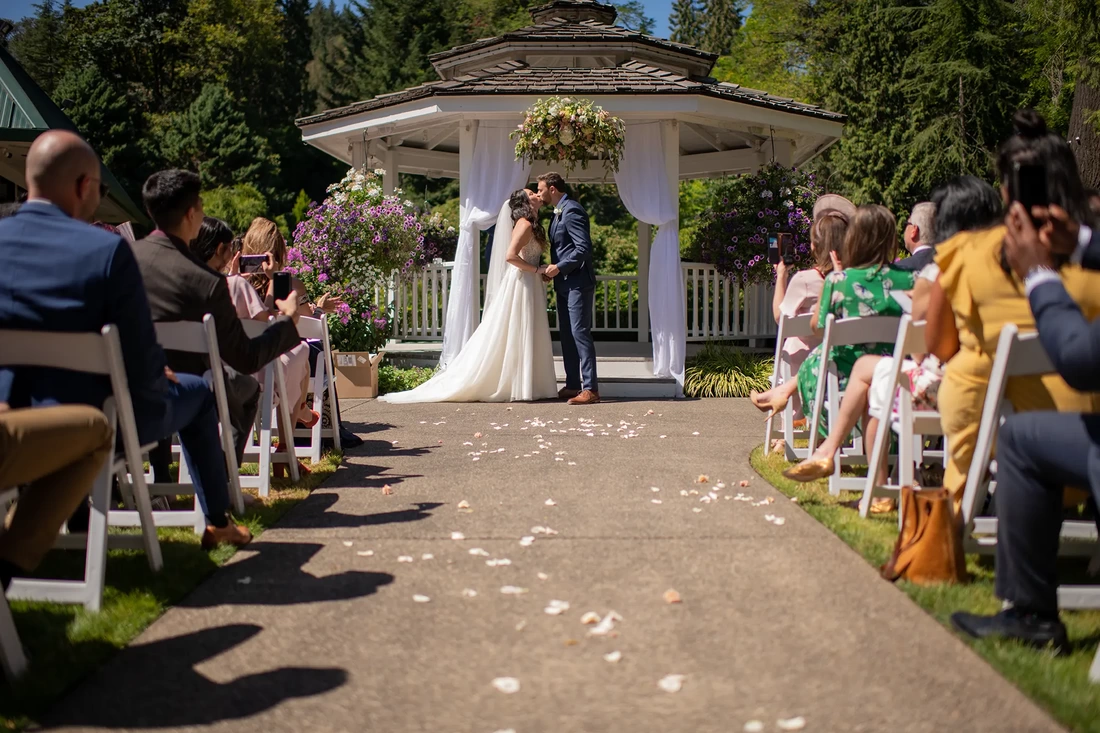 a couple kisses during the ceremony at a lakeside garden wedding 