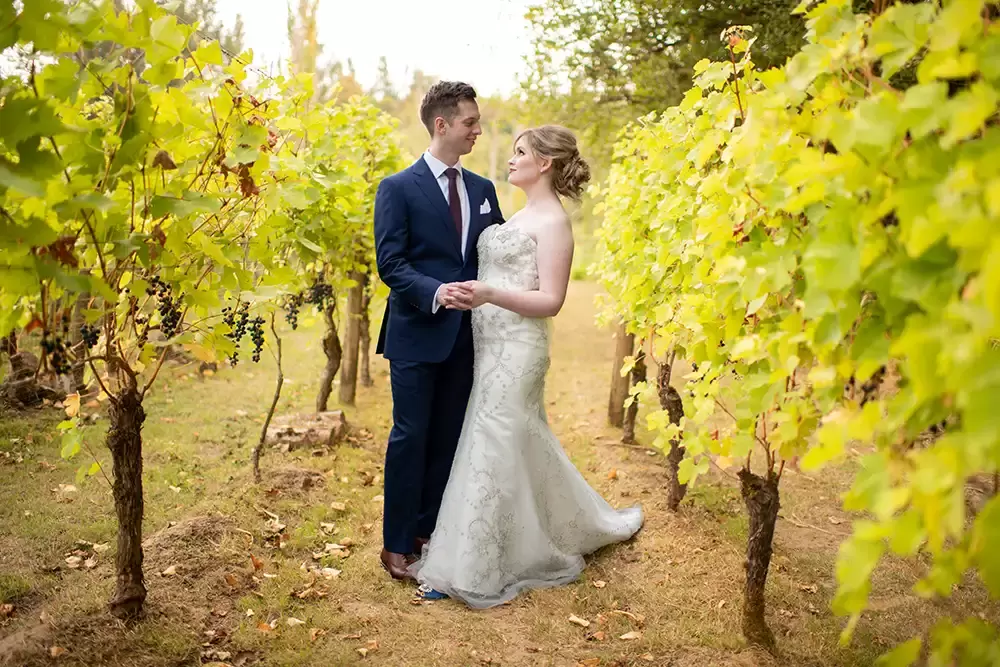 McMenamins Edgefield Weddings with Photographer Robert Knapp bride and groom hold hands like they are dancing surrounding by the rows of grapes in a vineyard