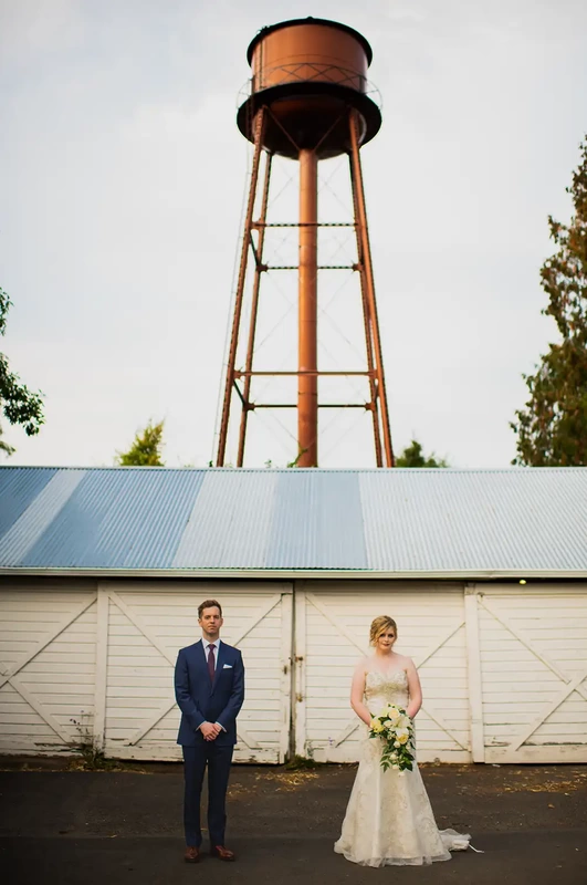 McMenamins Edgefield Weddings with Photographer Robert Knapp A bride and groom stand in front of a barn with a water tower over head. the image is interesting