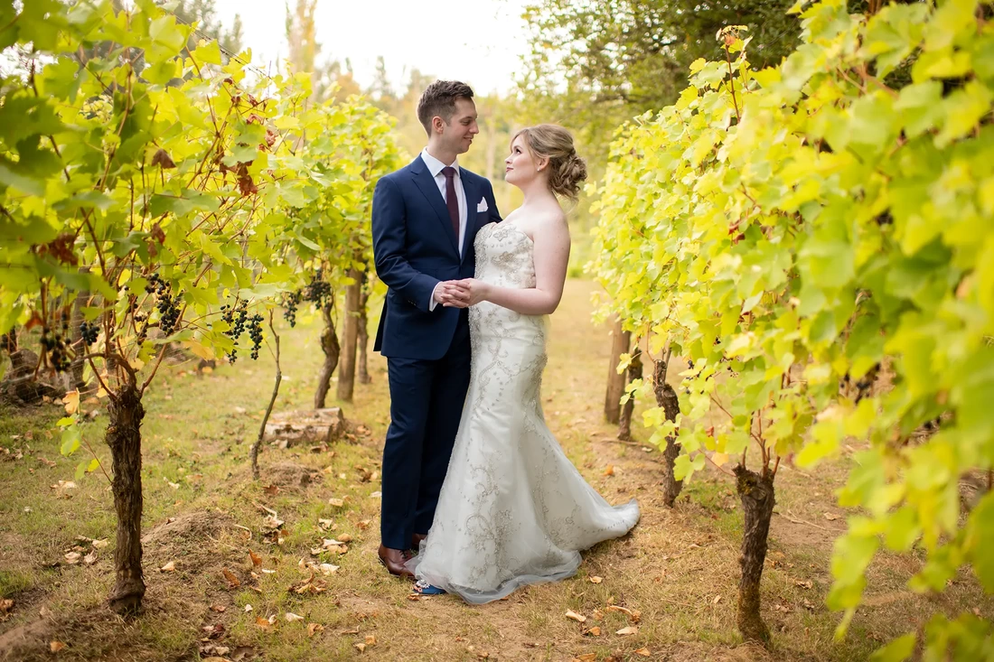 McMenamins Edgefield Weddings in the vineyard with a bride and groom full length photo shown the blue suit and dress
