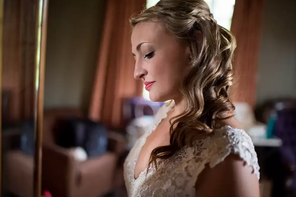 ​McMenamins Grand Lodge Weddings 
from Robert Knapp Photographer a bride stands in a ray of light reflected from the mirror. She looks down.