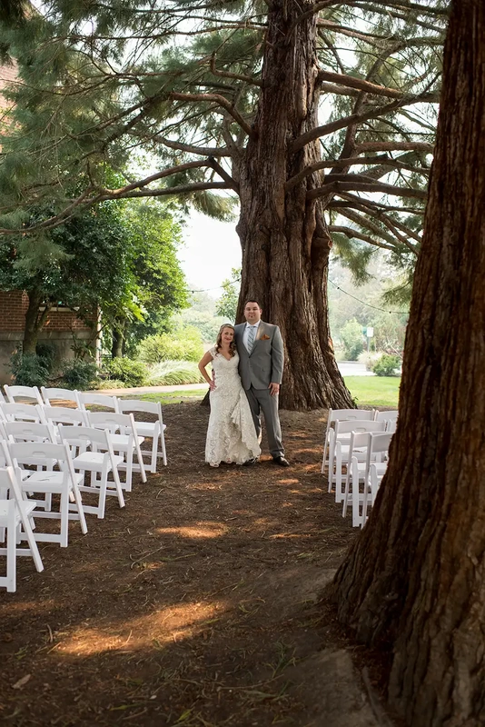 ​McMenamins Grand Lodge Weddings 
from Robert Knapp Photographer A bride and groom stand between redwood trees and chairs for the ceremony seating.