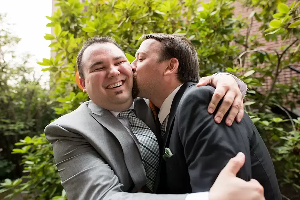 ​McMenamins Grand Lodge Weddings 
from Robert Knapp Photographerthe best man kisses the groom on the cheek