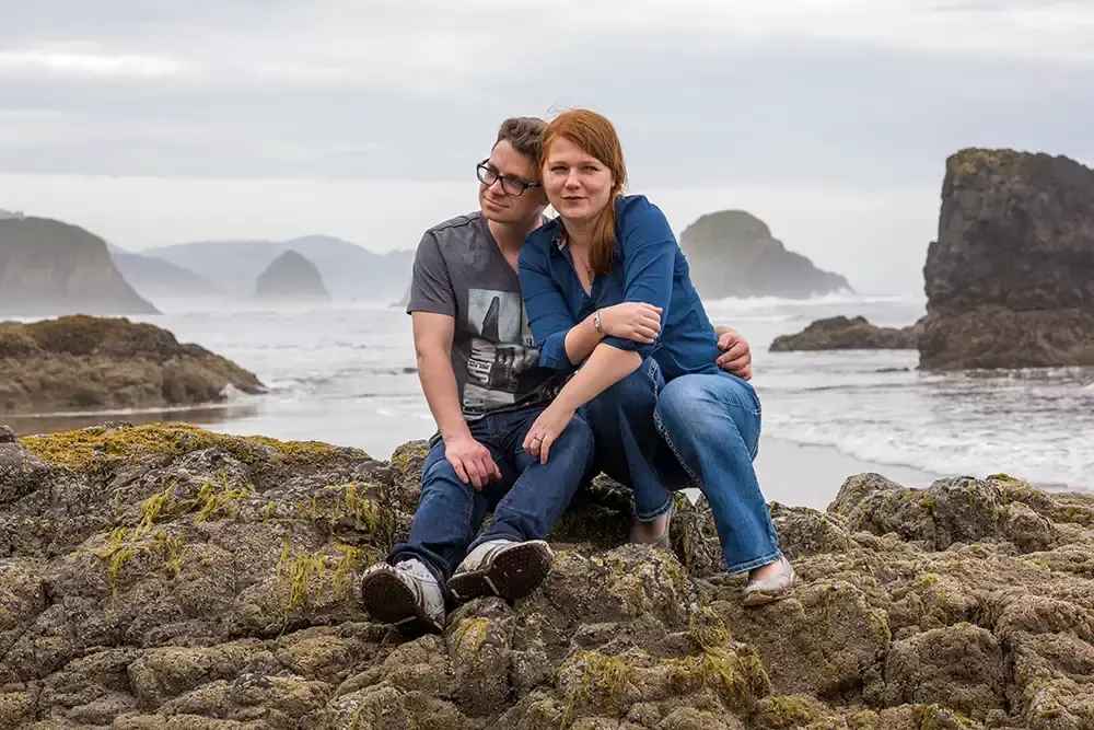 a couple sits high on a rock, the waves have them stranded Modern Art Photograph 
Engagement Photography Portland Oregon