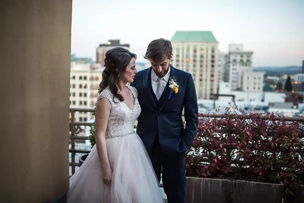 the bride looks to the groom and the groom looks down, they are up against the city skyline as photographed by ​​Modern Art Photograph 
Wedding Photographers in Portland
on location at the 
Portland Sentinel Hotel