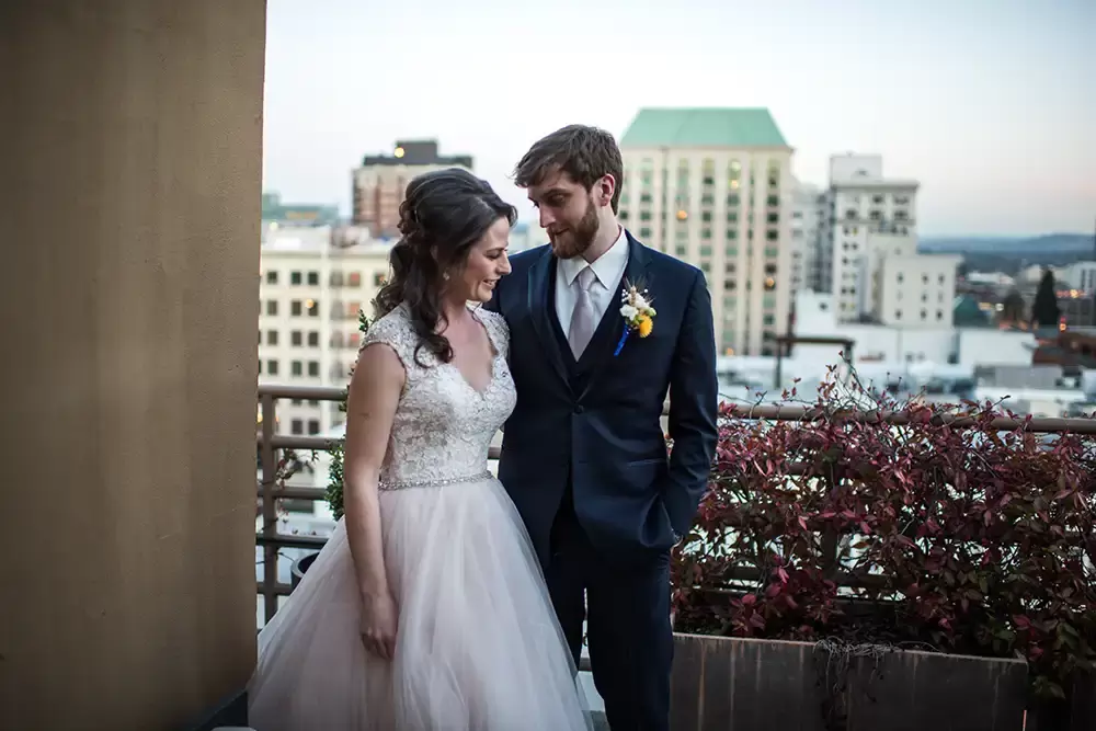 dusk lights the horizon of buildings in portland oregon. The bride and groom hold each other as photographed by ​​Modern Art Photograph 
Wedding Photographers in Portland
on location at the 
Portland Sentinel Hotel