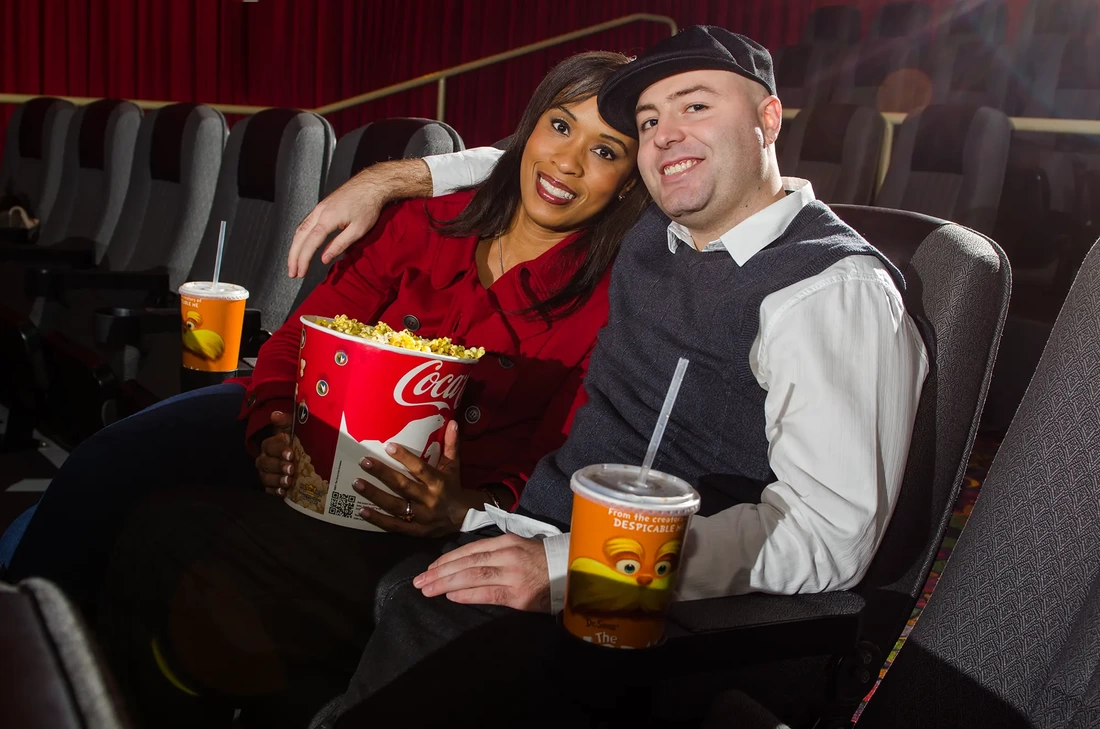 Nighttime Engagement Photos with Modern art Photograph in Portland Oregon, a couple sits in an empty movie theater together surrounded by popcorn and drinks. 