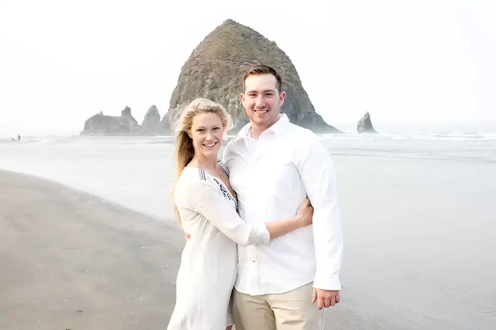 Oregon Coast Engagement Photos 
With 
Modern Art Photograph a couple smiles and looks to the camera on the beach 