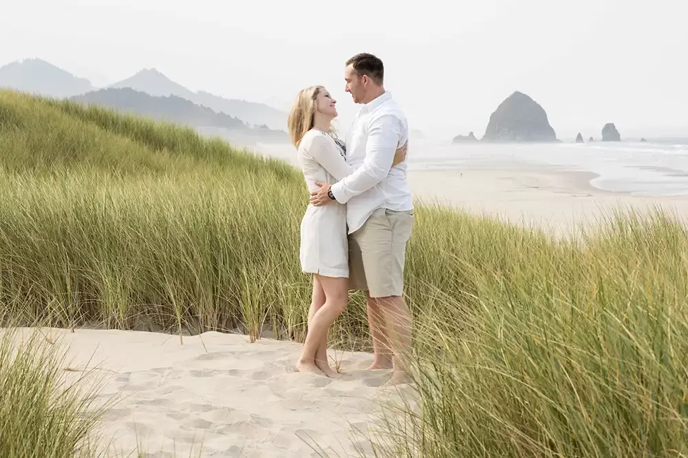 a couple look to each other for a photo of cannon beach Oregon Coast Engagement Photos 
With 
Modern Art Photograph