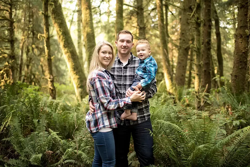 a family stands in glowing amber forest light Oregon Coast Engagement Photos 
With 
Modern Art Photograph