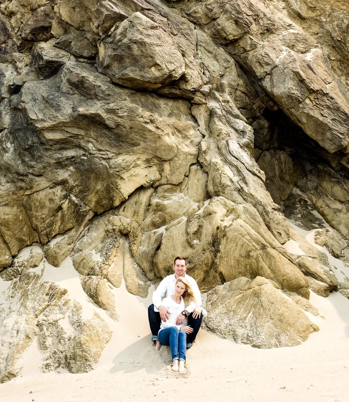 Oregon Coast Engagement Photos With Modern Art Photograph, The cliffs that rise from the sand on the beach make a beautiful background to this couple sitting in the sand