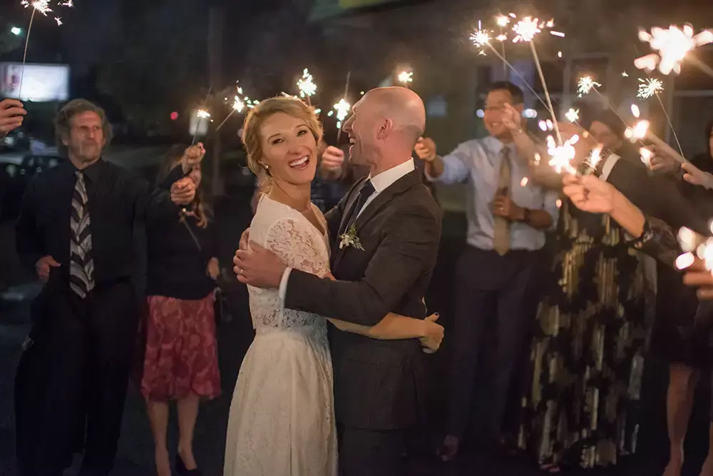 Oregon Wedding Photographers at Modern Art Photograph on location at opal 28 Wedding guests, surround the bride and groom with sparklers in hand they are very happy