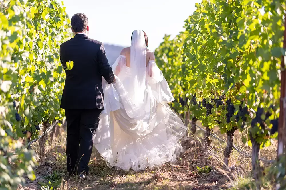bride and groom walk through the vineyard at the wedding venue
