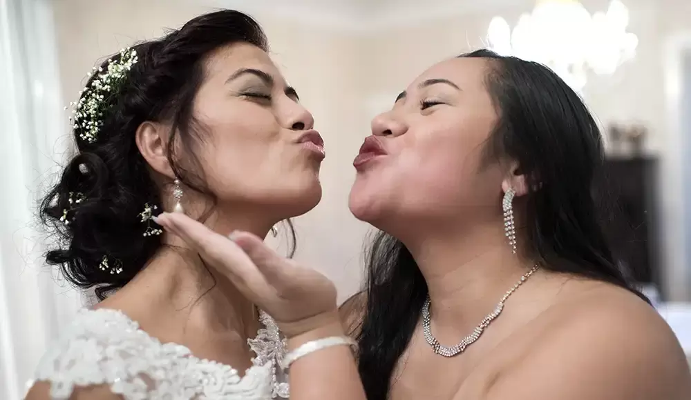 Grey gables estate, the bride and a bridesmaid make kiss faces to each other. 