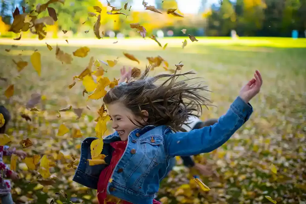 Portland Family Photographer robert knapp catches a moment where a little girl tosses a handful of leafs into the air