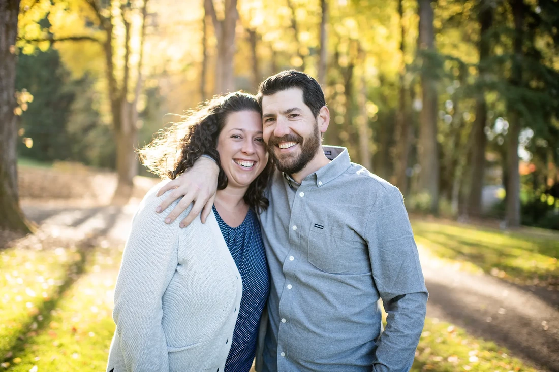 Portland Family Photography Robert Knapp photographs a couple looking to the camera with their arms around each other smiling in the sun and autumn colors 
