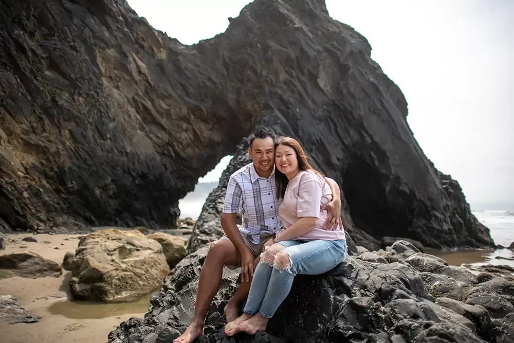husband and wife pose on the rocks next to the ocean Portland ​Family Photographer Robert Knapp - Book Today!