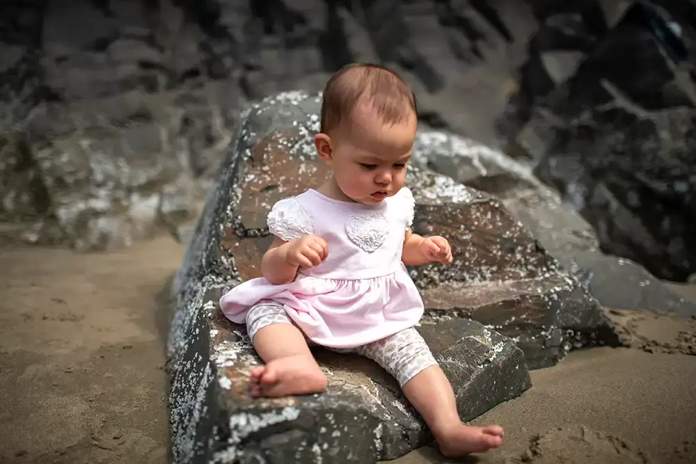 baby sits on a rock. She looks like sitting up is new to her Portland ​Family Photographer Robert Knapp - Book Today!​Family Photographer Robert Knapp in Portland - Book Today!