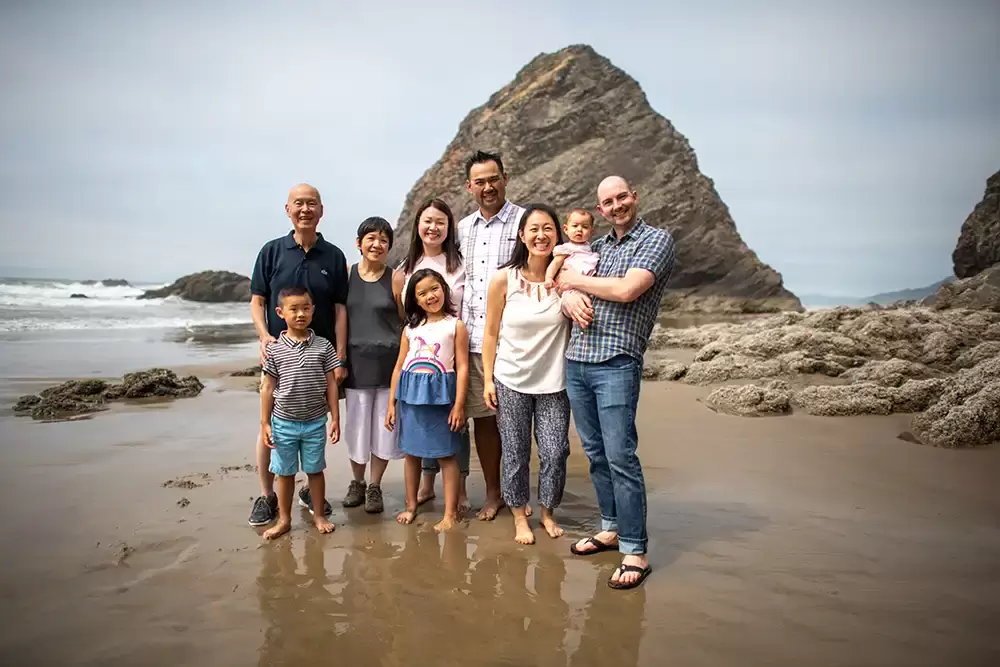 Family stares in the wet sand towards the camera. They smile waves in the background. Portland ​Family Photographer Robert Knapp - Book Today! ​Family Photographer Robert Knapp in Portland - Book Today!