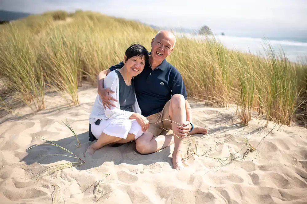 Oh, grandma and grandpa smile through the camera as they sit in the sand on the beach Portland ​Family Photographer Robert Knapp - Book Today!​Family Photographer Robert Knapp in Portland - Book Today!