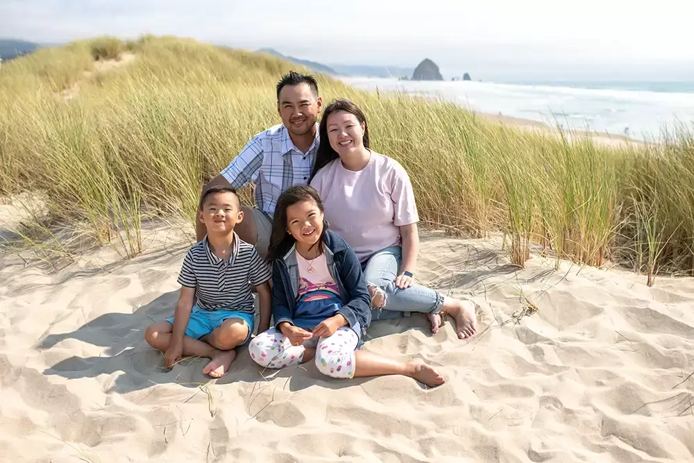 A family of four sits on the sand Portland ​Family Photographer Robert Knapp - Book Today!​Family Photographer Robert Knapp in Portland - Book Today!